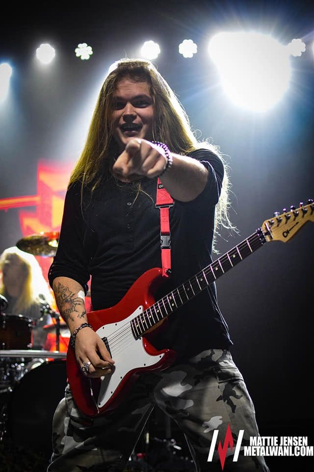 a man with long hair playing guitar on stage