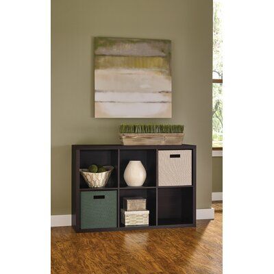 a shelf with baskets and other items on it in front of a green painted wall