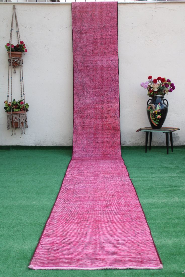 a pink rug on the ground next to a planter and potted flower arrangement