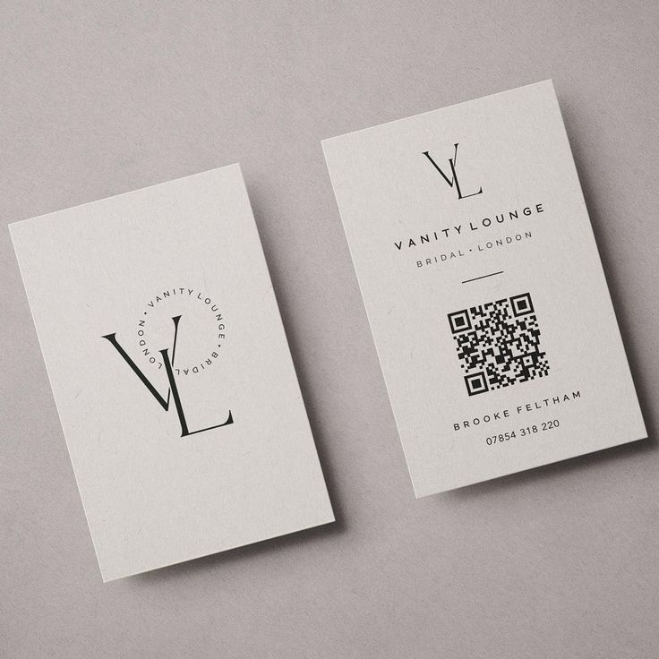 two business cards with q and v on them sitting next to each other in front of a gray background