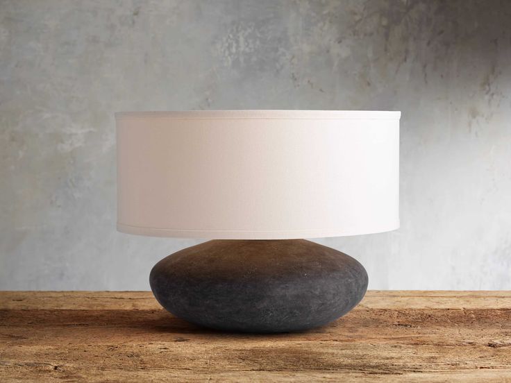 a lamp that is sitting on top of a wooden table next to a gray rock