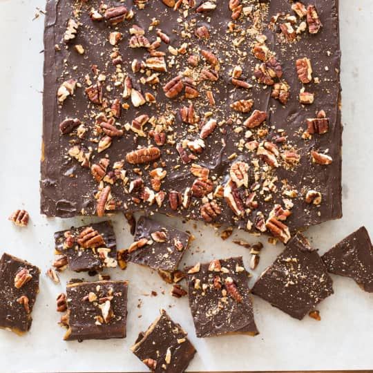 chocolate bark with nuts and pecans on top, surrounded by pieces of brownie