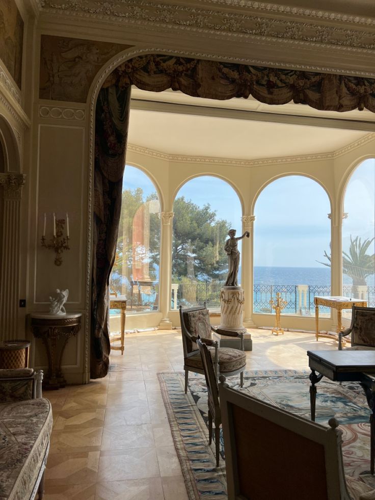 an ornate living room with large windows overlooking the ocean