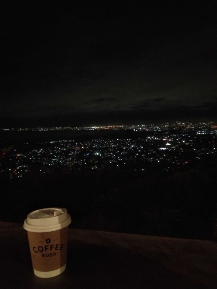 a cup of coffee sitting on top of a wooden table next to a night sky