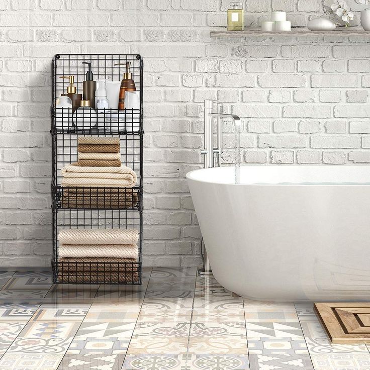 a white bath tub sitting next to a brick wall with towels on the rack in front of it