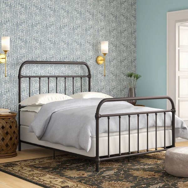 a bedroom with blue wallpaper and a metal bed frame in the middle, along with a rug on the floor