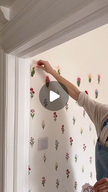 a man in overalls painting a wall with flowers on it