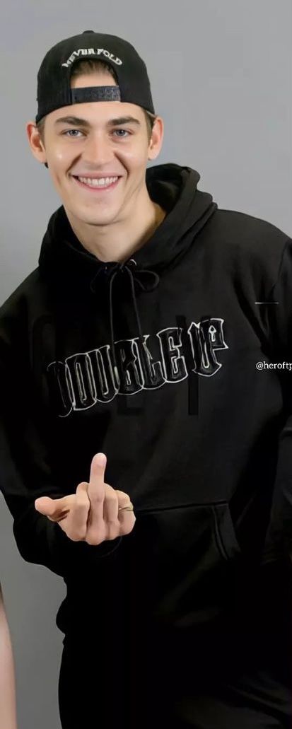 a young man wearing a black hoodie and pointing to the side with his finger