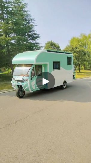 a green and white camper parked on the side of a road next to trees