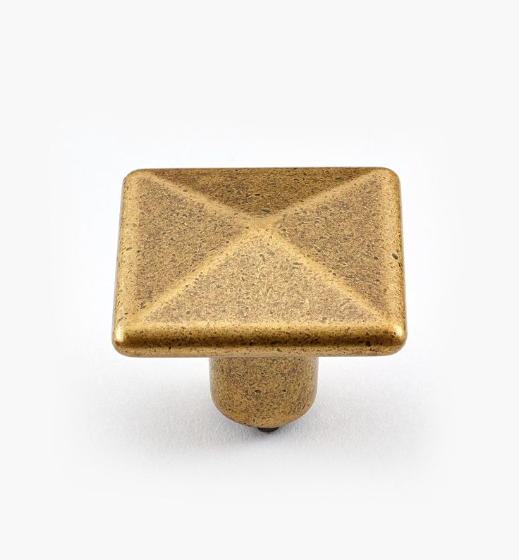 an antique brass square knob on a white background