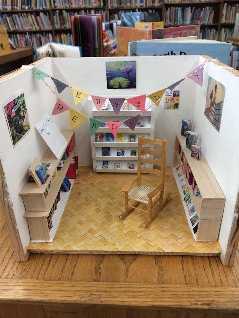 a doll house made to look like a library with bookshelves, chairs and pictures on the walls