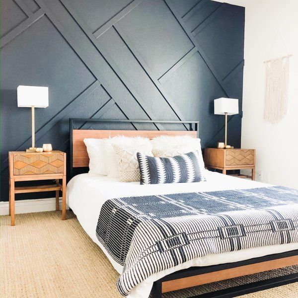 a bedroom with black and white bedding, two nightstands and a wooden headboard