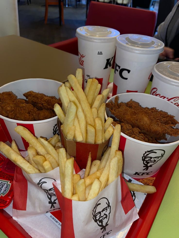 the tray is full of french fries and other foods on it, along with two cups of ketchup