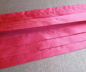 three pieces of pink paper sitting on top of a table