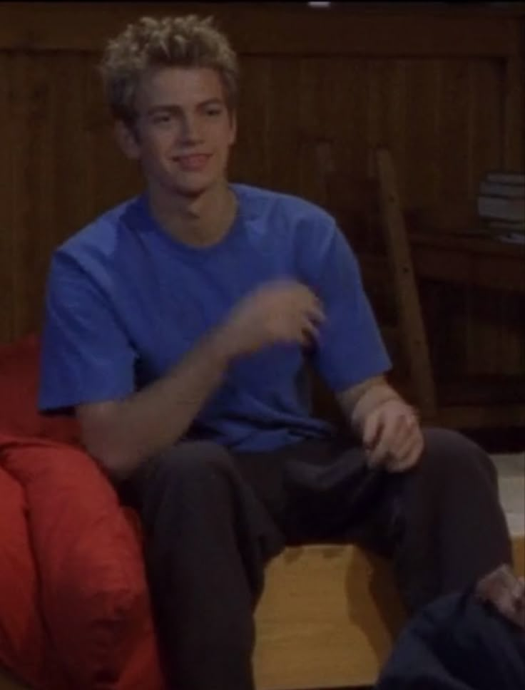 a young man sitting on top of a red couch