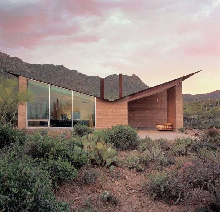 the desert house is surrounded by cactus and mountains