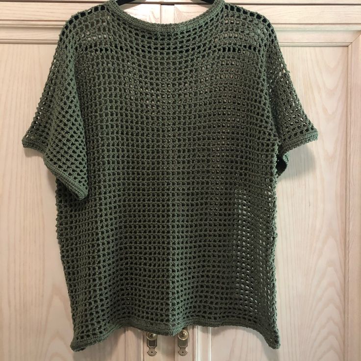 a green crocheted top hanging on a door