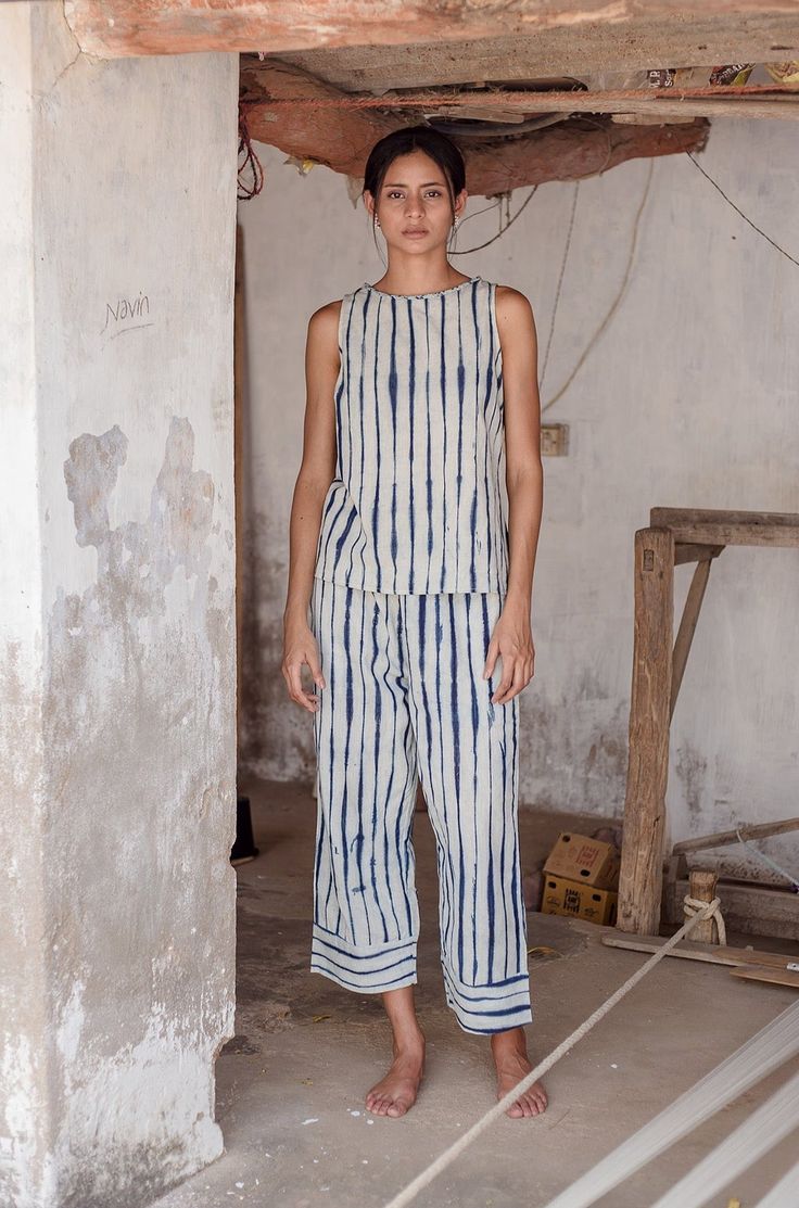 DETAILSThe Garima pant is an easy pull-on style with an elasticated waist with a contrasting hand braided drawcord, wide legs and a cropped length. MATERIALSIts eye catching pattern is achieved using a unique clamp dyed shibori technique to create a hand drawn like stripe pattern. We use natural indigo dyes to create a rich blue hue. Our naturally dyed kora fabric is an ideal weight for the summer and provides ease of wear throughout the warm season. With a unique hand feel due to the hand weavi Shibori Outfit, Shibori Fashion, Shibori Clothing, Indigo Fashion, Shibori Dress, Fashion Over Fifty, Fabric Dyeing Techniques, Shibori Techniques, Natural Indigo Dye