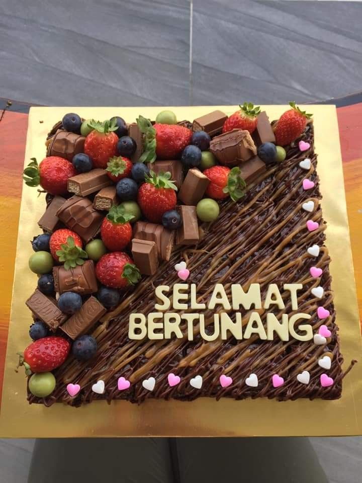 a chocolate cake with strawberries, raspberries and chocolate bars on it that says selamat bertunang