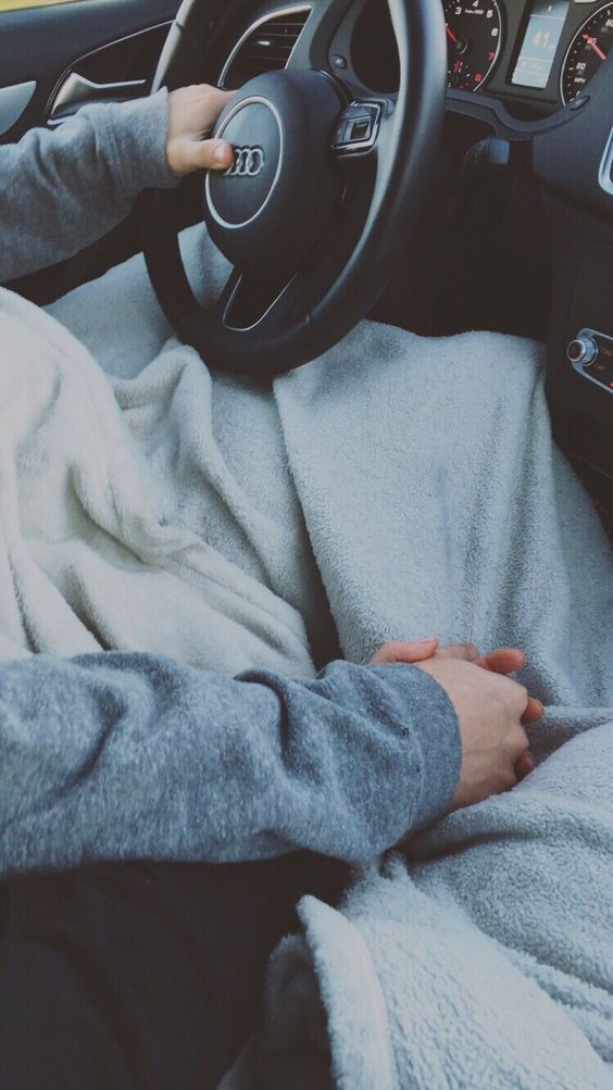 a person is sitting in the driver's seat of a car with a blanket on