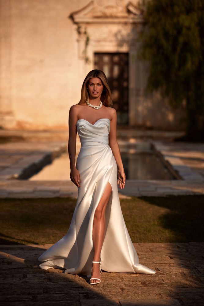 a woman in a white dress is standing outside