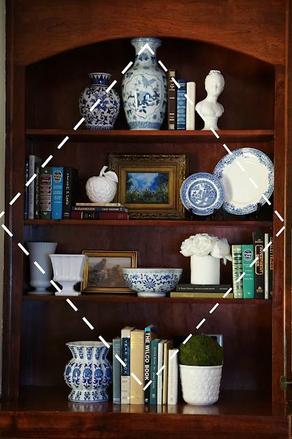 a wooden book shelf filled with books and vases