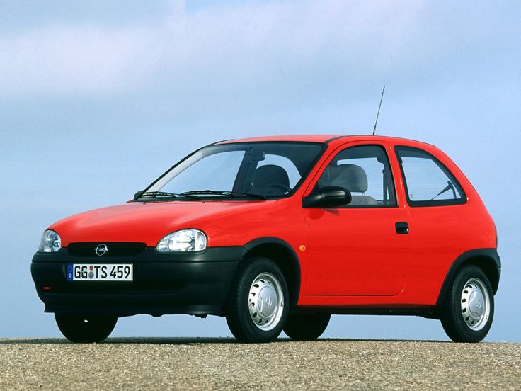 a small red car parked on top of a sandy beach next to the ocean in front of a blue sky