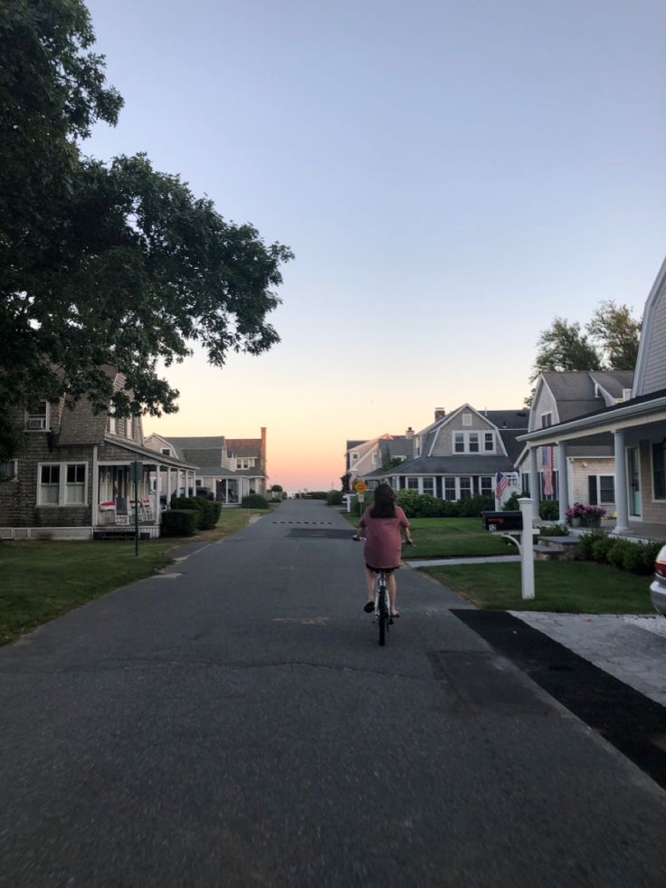 a person riding a bike down a street with houses in the backgrouds