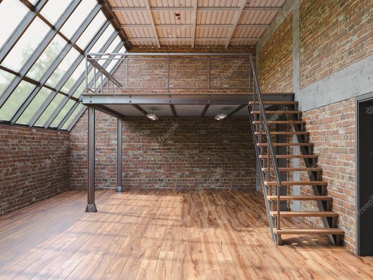 an empty room with brick walls and wooden floors, stairs leading up to the second floor