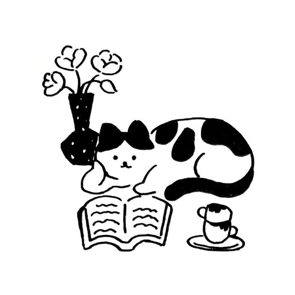 a black and white cat laying on top of an open book next to a plant