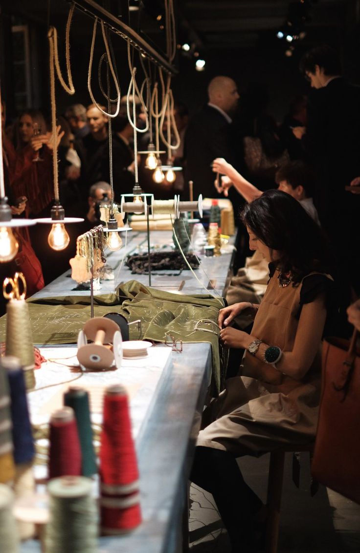 a group of people sitting at a long table in a room with many different items on it