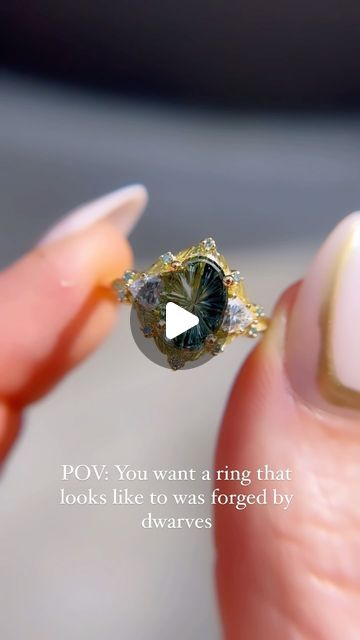 a woman's hand holding a ring that looks like it is surrounded by diamonds