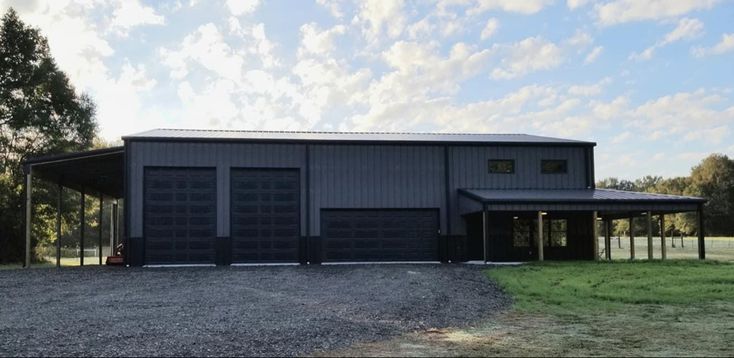 a two car garage sitting on top of a gravel road next to a field and trees