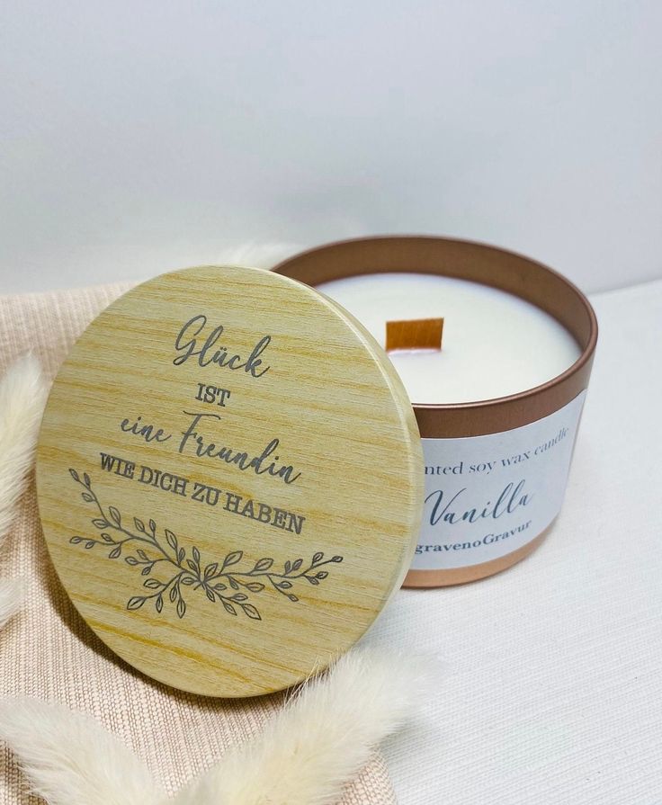 a candle with a wooden lid sitting on top of a white cloth next to a small jar