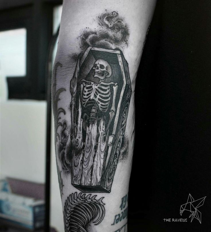 a black and white photo of a skeleton with a cross on it's arm