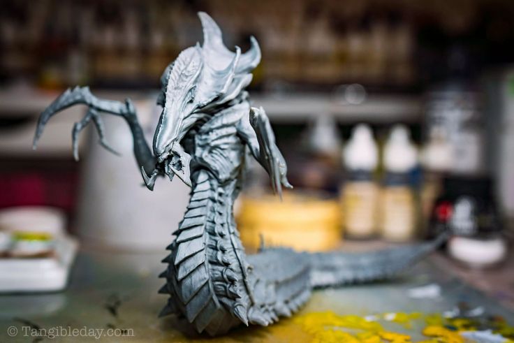 a dragon statue sitting on top of a table next to paint and other items in the background