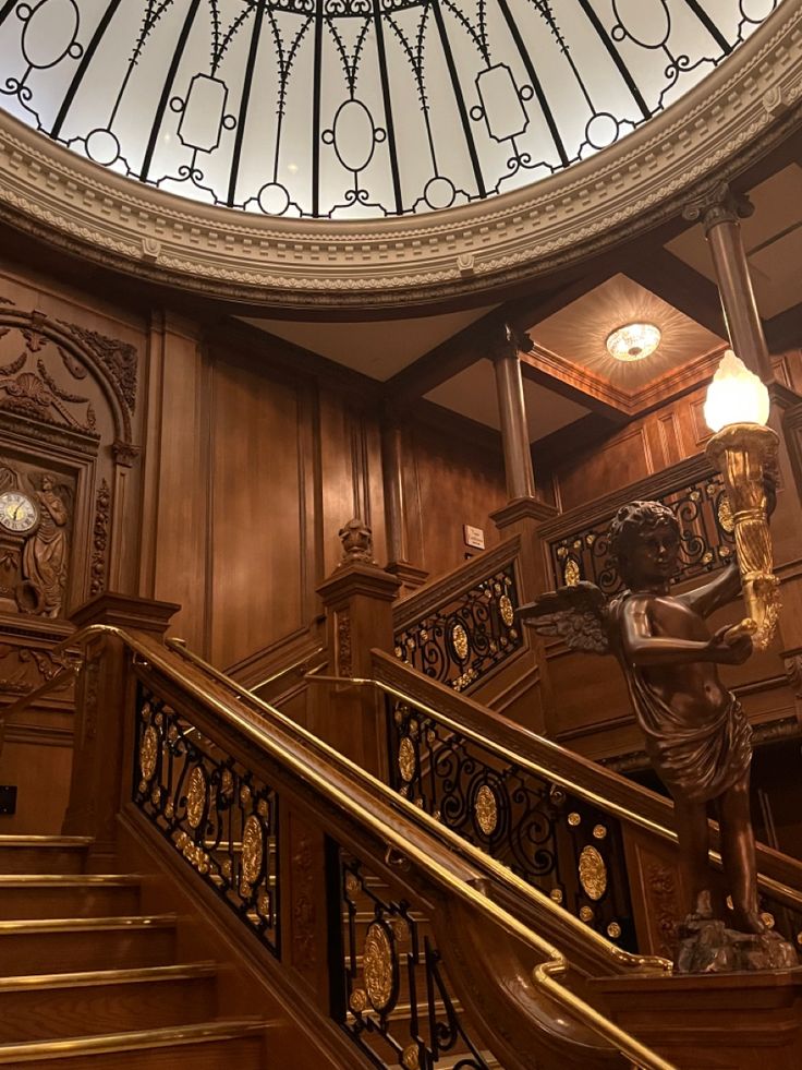 an ornate stair case in a building with a glass dome above the railing and clock on the wall