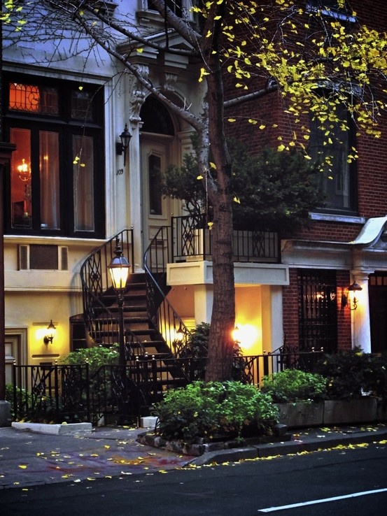 an apartment building at night with lights on the windows and stairs leading up to it