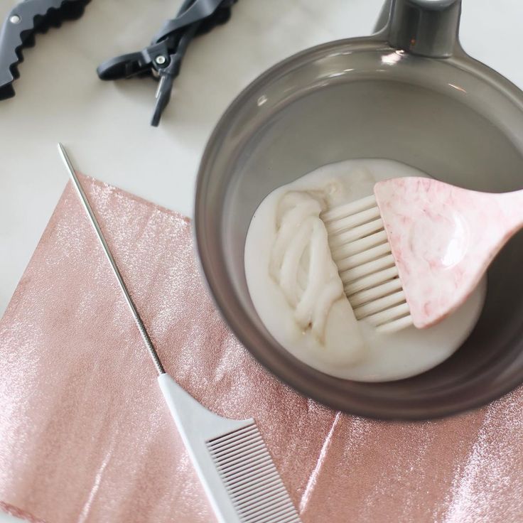 a hairbrush and comb in a container on a pink table cloth next to scissors