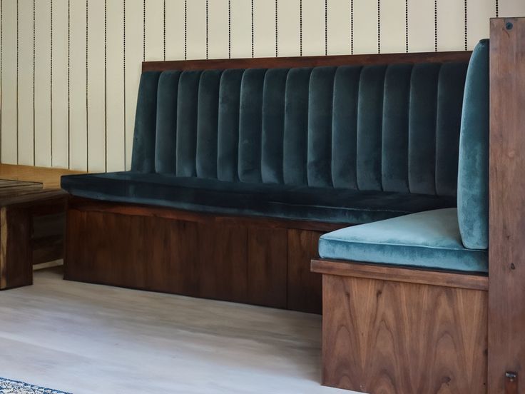 a wooden bench with blue velvet upholstered seat and back rest in a room