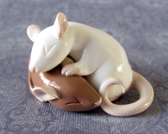 a white and brown toy mouse sitting on top of a blue tableclothed surface