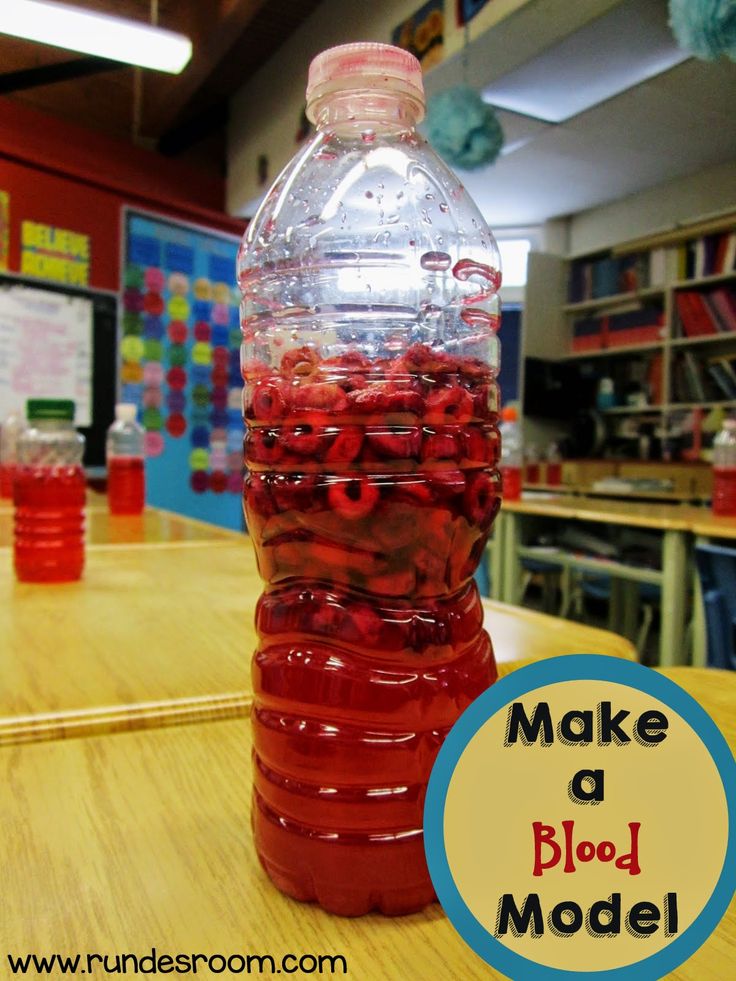 a plastic bottle filled with red liquid sitting on top of a table next to a wooden table