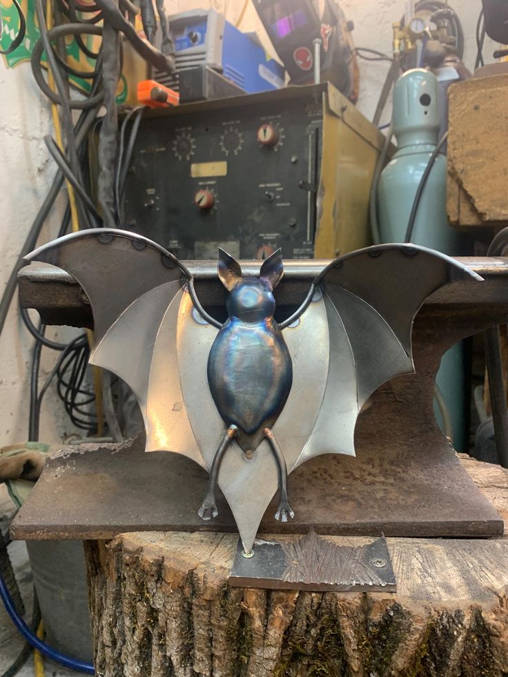 a metal bat sculpture sitting on top of a piece of wood