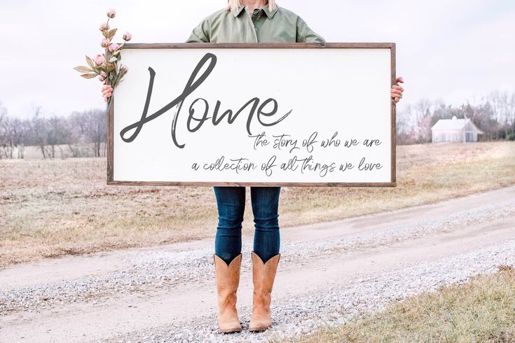 a man holding up a sign that says family is everything on the side of a dirt road