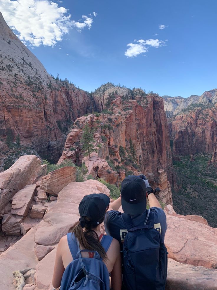 two people sitting on the edge of a cliff