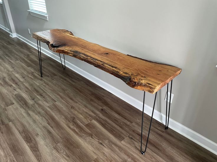 a wooden bench sitting on top of a hard wood floor next to a white wall