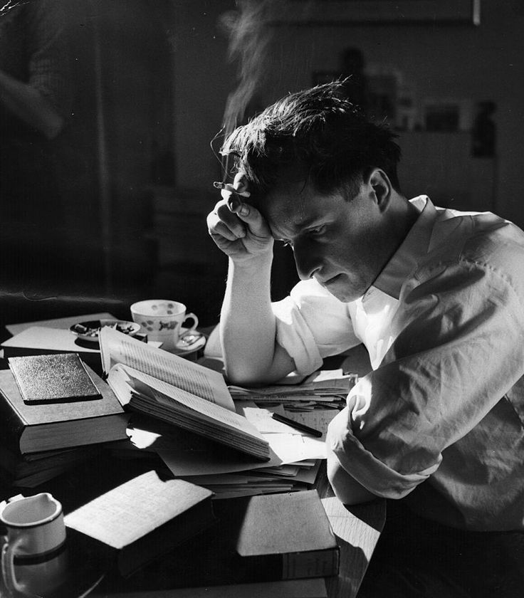 a man sitting at a table with his head in his hands while reading a book