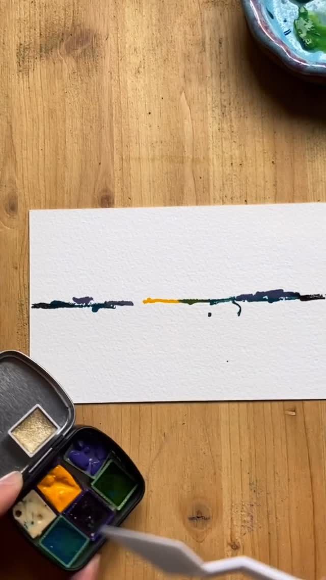 a person is painting on paper with watercolors