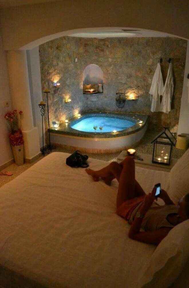 a woman laying on top of a bed in front of a jacuzzi tub