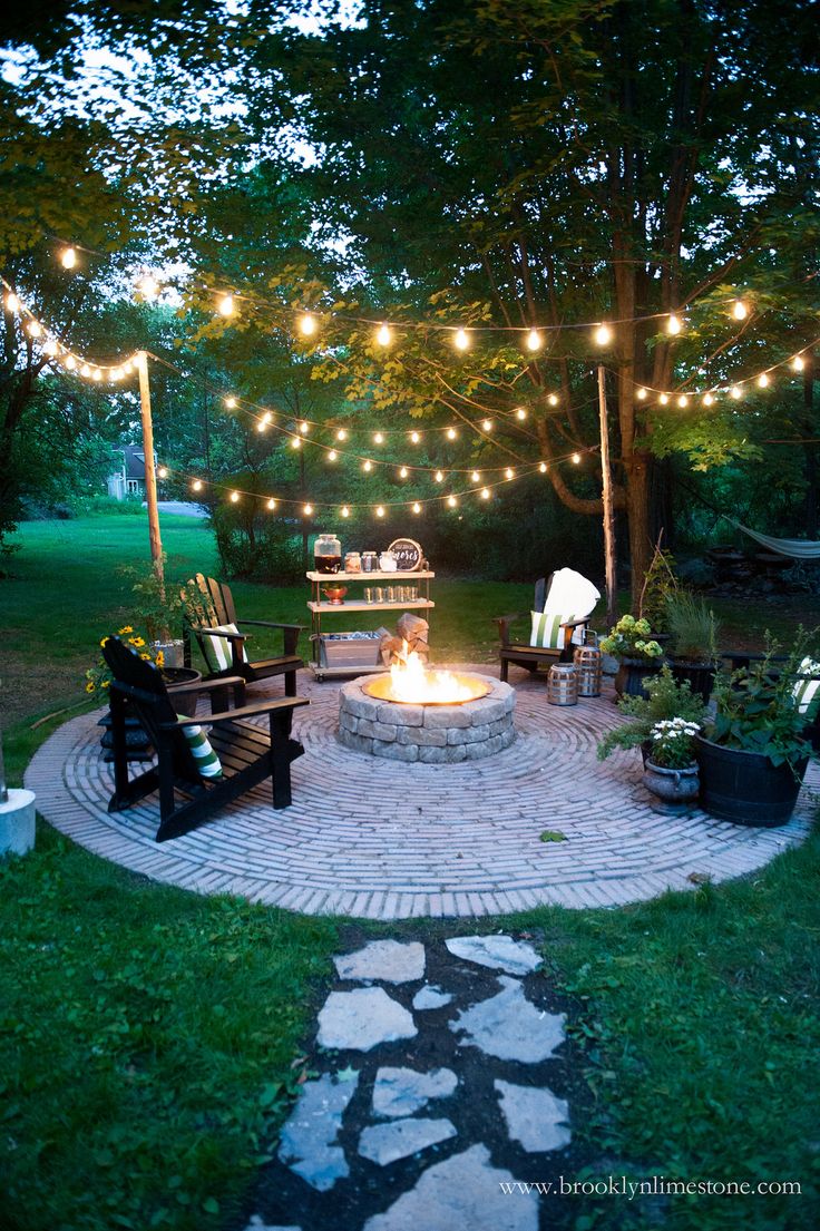 an outdoor fire pit with lights strung over it